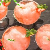 Frozen strawberry Tiki cocktails served with lime and fresh fruit at The Sugar Cane Bar in Clapham, London
