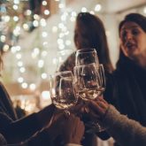 Group of women enjoying a girls’ night out in London, toasting with wine glasses under twinkling lights at a festive bar