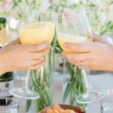 Two women toasting with orange cocktails at a hen party bottomless brunch in Clapham