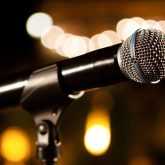 Close-up of a microphone on stage with warm blurred lights in the background, capturing the atmosphere of a live music night at The Sugar Cane bar in London.